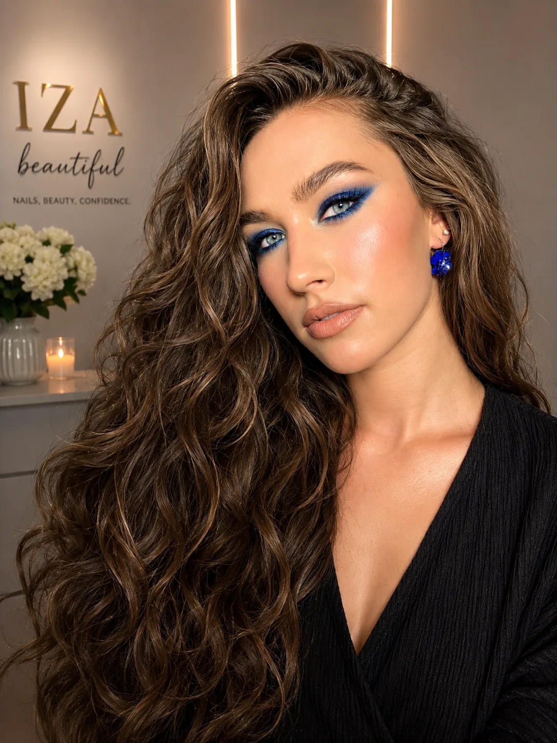 Model wearing vivid blue eye makeup and matching earrings at Iza Studio